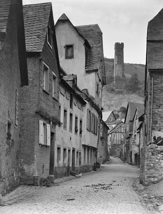Cobblestone street lined with old buildings and a castle